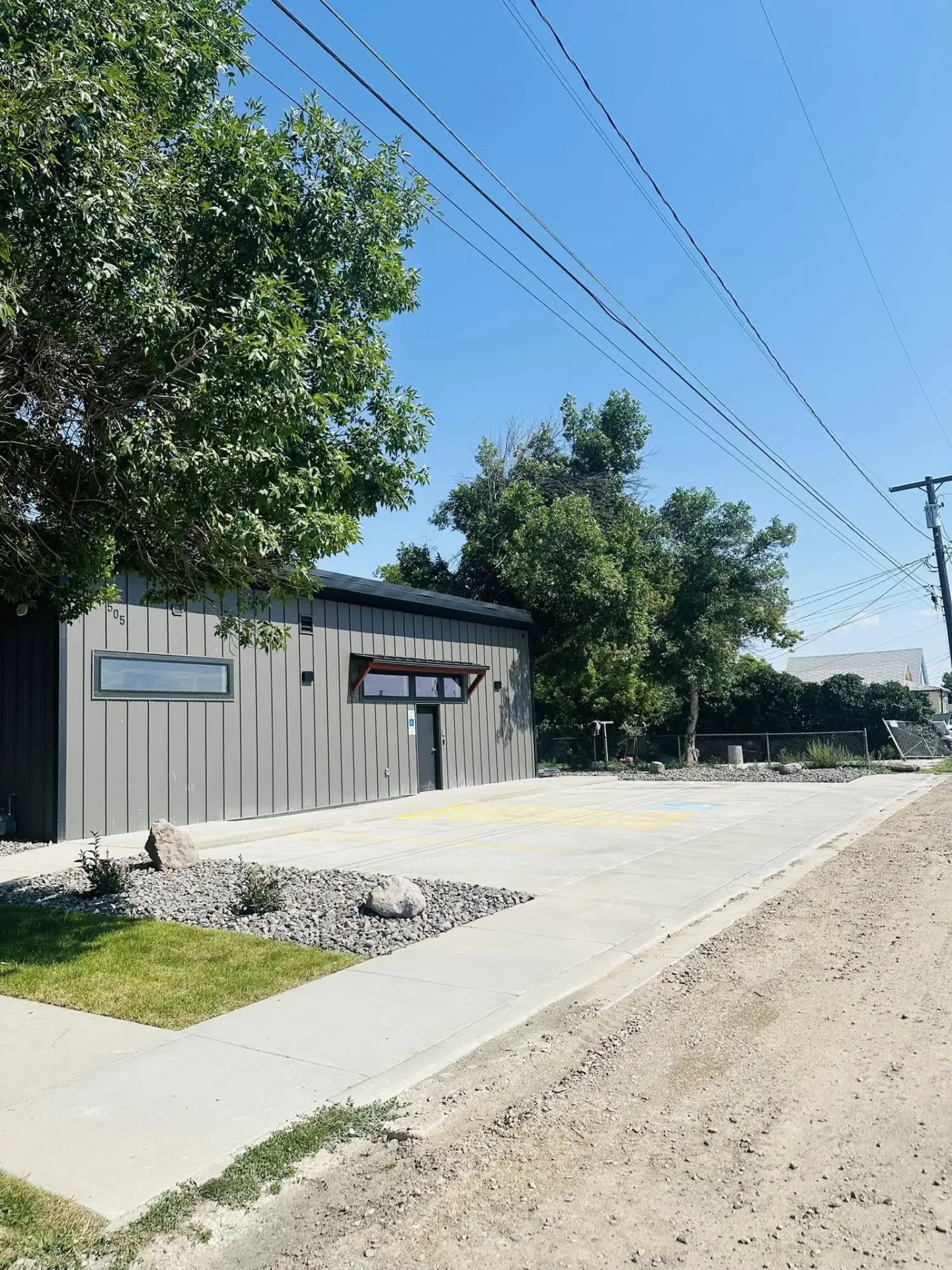 Completed dark grey building with fresh concrete apron and landscaping