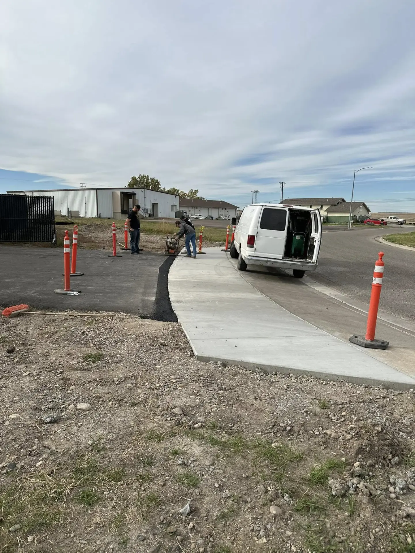 Crew compacting base material beside a newly poured concrete approach